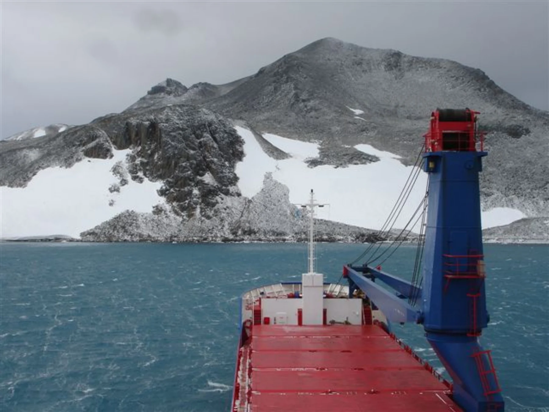 Buque de carga junto a una costa montañosa nevada